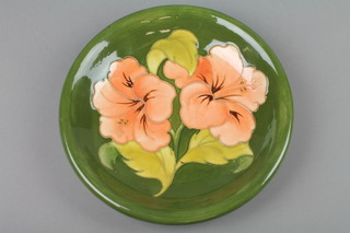 A Walter Moorcroft 1430's green ground dish decorated Hibiscus, with printed label and monogram 9" 