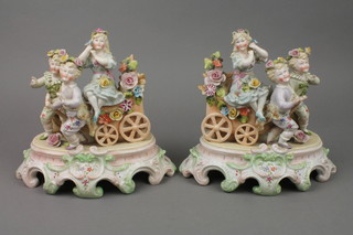 A pair of 19th Century Continental bisque groups of 2 boys pulling a girl in a wagon with applied flowers and rococo bases 8" 