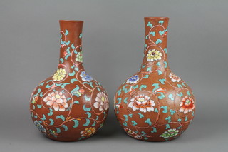 A pair of 19th Century brown glazed bottle vases decorated in coloured enamels with formal scrolling flowers 14"