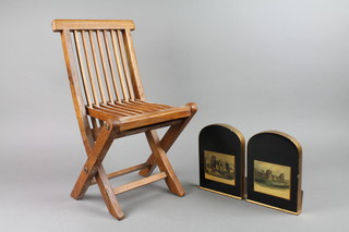 A teak framed slatted folding childs chair together with a pair of lacquered book ends decorated prints of St Mary's Church Eastbourne and Pevensey castle