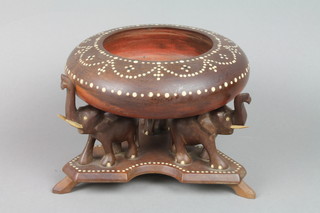 A circular turned Indian hardwood bowl with inlaid ivory decoration supported by 3 elephants on a triform base 9"