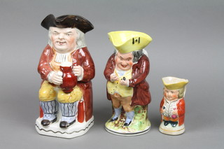 A 19th Century Toby jug in the form of a seated gentleman holding a jug of ale 9" and 2 others 8" and 5"