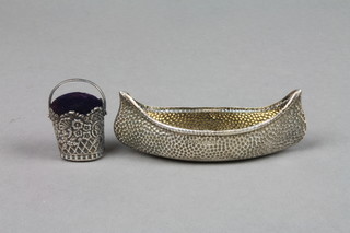 A Continental repousse silver pail pin cushion, 1.7" to handle and an Edwardian silver miniature kayak 3.5" Birmingham 1904 