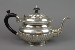 A white metal teapot with demi-fluted decoration and hardwood mounts