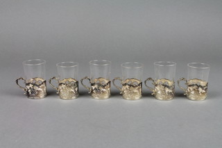 A set of 6 Edwardian silver tot holders decorated with figures at country pursuits with clear glass inserts