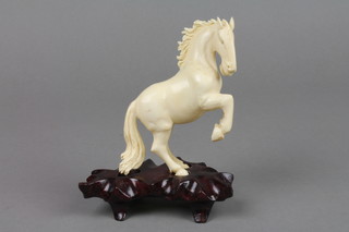 A carved ivory figure of a rearing horse on a hardwood stand 4"