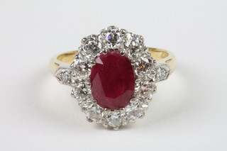 An 18ct yellow gold ruby and diamond cluster ring, the central oval cut ruby approx 2.50ct surrounded by 10 brilliant cut diamonds, approx 1.35ct with diamond shoulders