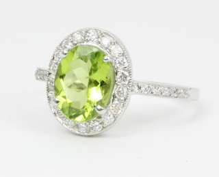 An 18ct white gold peridot and diamond cluster ring, the oval cut peridot approx. 3ct surrounded by brilliant cut diamonds and brilliant cut diamond shoulders