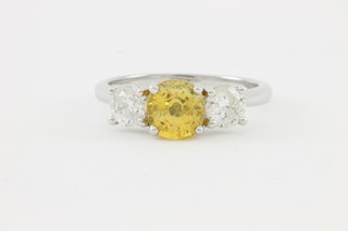 An 18ct white gold cushion cut yellow sapphire ring approx. 1.75ct flanked by 2 brilliant cut diamonds approx 0.94ct