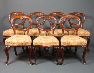 A set of 7 mid Victorian carved mahogany balloon back dining chairs, the crests with family armorial and stuff over seats, serpentine legs