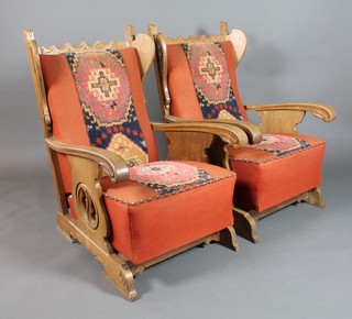 A pair of Continental Art Deco carved oak show framed winged armchairs upholstered in orange material 