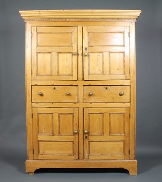 A 19th Century pine press cabinet with moulded and dentil cornice, the upper section fitted a cupboard enclosed by panelled doors, the base fitted 2 long drawers above a double cupboard, on bracket feet 77"h x 56"w x 20"d 