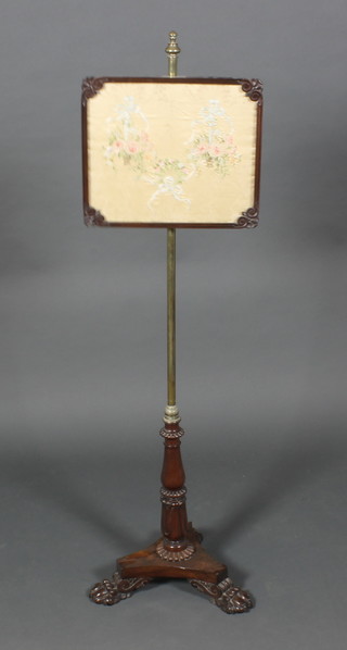 A William IV rosewood and brass pole screen with silk stitchwork banner, raised on a fluted column with triform base and paw feet 