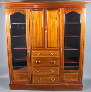 An Edwardian mahogany triple wardrobe converted to a display cabinet with moulded cornice, the centre section fitted a cupboard enclosed by panelled doors above 4 long drawers with brass swan neck drop handles, flanked by a pair of cupboards with adjustable shelves enclosed by bevelled panelled glass doors 84"h x 76"w x 23"d 