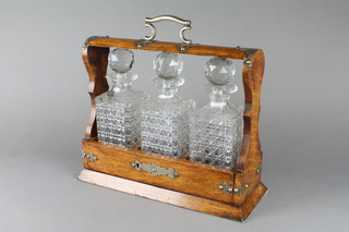An oak and silver plated mounted 4 bottle tantalus complete with 4 hobnail cut decanters
