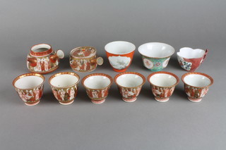 A Kutani Sake set decorated with bands of figures comprising 6 cups, a jug (lacking lid) and 1 other jug with lid (both f) and 3 other items