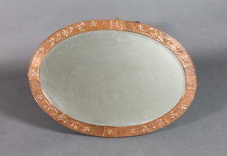 An Art Nouveau oval bevelled plate wall mirror contained in an embossed copper frame with floral decoration 22 1/2"w x 33 1/2", some spots to mirror 