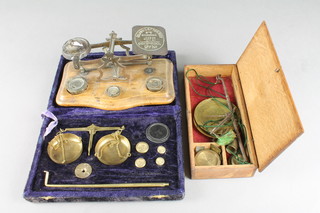 An 18th/19th Century brass and steel scales, a pair of postal scales complete with weights and a pair of gold scales in a plush box