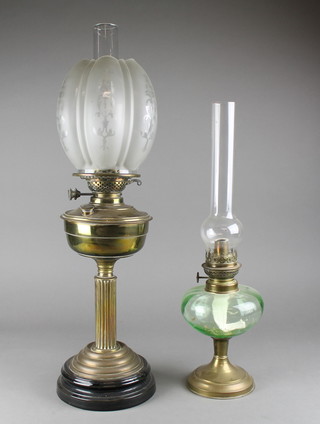 A brass oil lamp raised on a reeded column with opaque shaped and chimney 25" and a green glass oil lamp chimney 20"