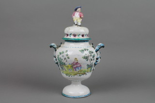 A 19th Century faience waisted baluster vase and cover,the finial in the form of a seated gentleman, the body with scroll handles and panels of flowers and a mother and child in a country garden, f, 13"