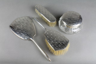 A 4 piece silver mounted dressing table set comprising cut glass powder bowl, hair brush, clothes brush and hand mirror, the engraved decoration with stylised leaves