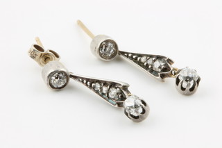 A pair of Edwardian gold diamond drop earrings with a single stone suspending a fan shaped drop terminating in a brilliant cut stone