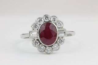 An 18ct white gold ruby and diamond cluster ring, the oval cut ruby approx. 1.4ct surrounded by approx 0.4ct of brilliant and baguette cut diamonds
