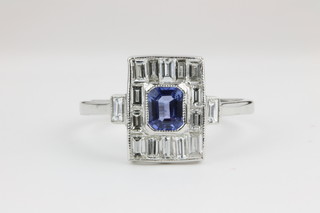 An 18ct white gold sapphire and diamond dress ring, the centre stone surrounded by baguette cut diamonds 