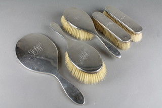 A silver 5 piece dressing table set comprising 2 hair brushes, 2 clothes brushes and a mirror, all engraved with a monogramme, London 1914