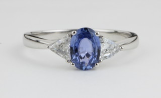 An 18ct white gold sapphire and diamond dress ring, the oval cut sapphire approx. 0.87ct flanked by triangular cut diamonds approx 0.3ct