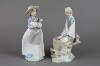 A Lladro figure of a lady sitting on a tree stump looking at a bird 10" and a Nao figure of a girl with puppies 11"