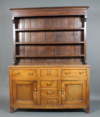 A Georgian oak dresser, the raised back with moulded cornice fitted 3 shelves, the base fitted 3 short drawers flanked by 2 long drawers above a double cupboard with brass escutcheons and handles 78~"h x 58"w x 19"d 