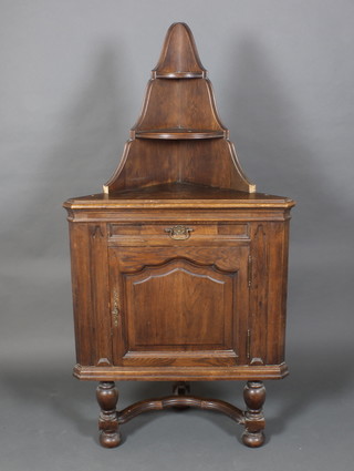 A 19th Century Continental oak corner cabinet, having 2 raised niches to the back, the base fitted a drawer above a cupboard enclosed by a panelled door, having a wavy Y shaped stretcher, raised on bun feet 65 1/2"h x 33"w x 18"d 