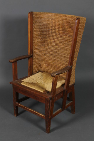 An Orkney style pine lambing chair with caned back and woven rush drop in seat, raised on square supports