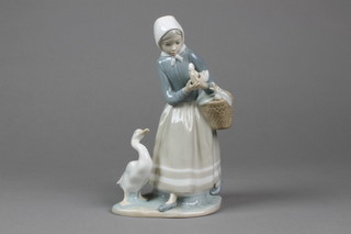 A Lladro figure of a goose girl holding a basket of goslings 9"