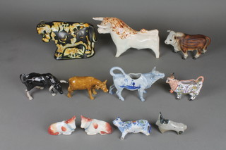 A pair of Staffordshire figures of reclining cows 3", a collection of cow creamers, bulls and figurines