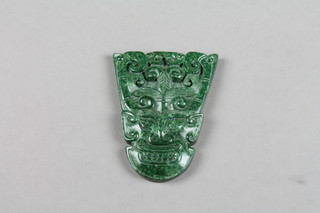 A carved jadeite pendant in the form of a stylised mask 3" 
