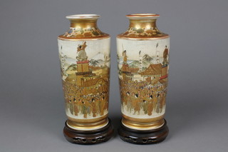 A pair of fine Meiji period Satsuma tapered cylindrical vases, profusely decorated with crowded townscapes and banners and distant mountains.  Seal marks to the bases, with hardwood stands and original fitted box, 10"h