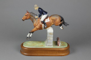 A Royal Worcester horse racing group "Stroller and Marion Cokes", showing a rider up jumping over a fence, 11", on a wooden socle