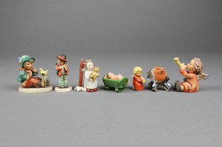 7 Goebels figures - seated angel 359, a robin, a kneeling angel, a baby in a crib, an angel with bear 2", a violinist 198/4 and singing lesson 63 3"