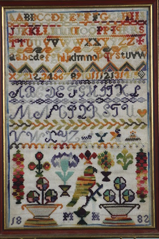 A Victorian wool work sampler with alphabet and bird plant pots, dated 1882, monogrammed PIH 15" x 10"