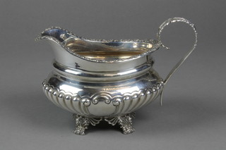 A Victorian silver demi-fluted cream jug with floral rim and acanthus handle on claw feet, Sheffield 1894, approx. 13 ozs 