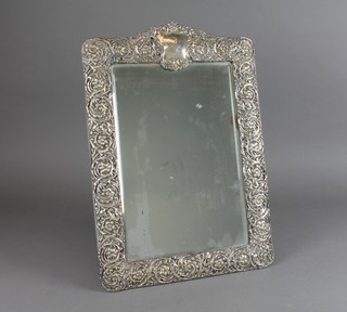 An Edwardian repousse silver easel dressing table mirror, profusely decorated with formal scrolling flowers and cartouche engraved with a monogram 21" x 14" 