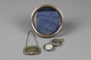An Edwardian circular silver photograph frame, Sheffield 1902, 4", a silver spirit label and a plated sovereign case 