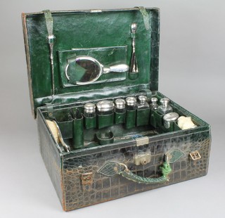 A Victorian hammer pattern silver mounted toilet set comprising 8 mounted cut glass jars, 2 hair brushes, 2 clothes brushes, a hand mirror, button hook and shoe horn, contained in a green crocodile leather case