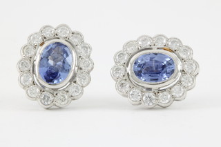 A pair of white gold sapphire and diamond cluster ear studs, sapphires approx 0.5ct each, surrounded by 14 brilliant cut diamonds