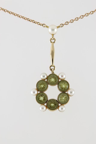 An Edwardian 9ct peridot and seed pearl open pendant on a ditto chain
