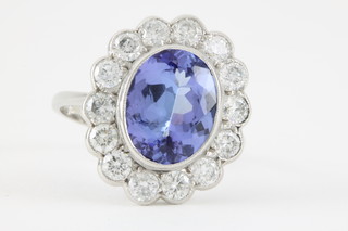 An 18ct white gold oval tanzanite and diamond cluster ring, the centre stone approx 3.25ct surrounded by 14 brilliant cut diamonds, approx 1.2ct 