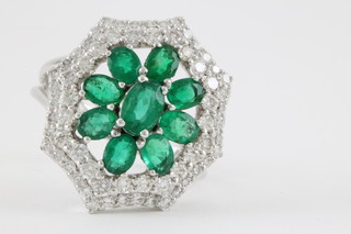 A 15ct white gold diamond and emerald cluster ring 