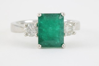 An 18ct white gold emerald and diamond and ring, the emerald approx. 2.40ct flanked by 2 brilliant cut diamonds approx. 0.47ct